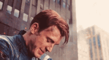 a close up of a man 's face in front of a building with his head down .