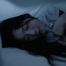 a woman is sleeping in a dark room