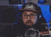 a man with glasses and a hat that says harts on it