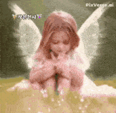 a little girl with angel wings is sitting on a pile of sand