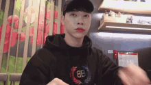 a man wearing a black hoodie with the letters 8b on it