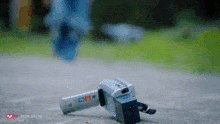 a video camera is laying on the ground in front of a green field with a mnet logo in the background