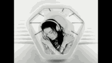 a black and white photo of a woman wearing headphones and a clock