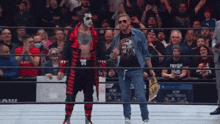 two men are standing in a wrestling ring with a crowd watching .