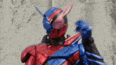 a red and blue robot is standing in front of a wall and making a funny face .