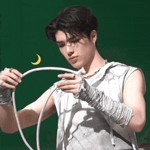 a young man is holding a rope with a yellow crescent moon behind him