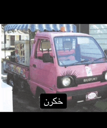 a pink suzuki truck with a blue awning on top of it