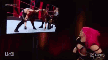 a woman is wrestling another woman in a wrestling ring with a referee in the background .