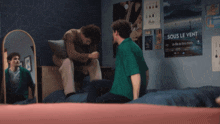 a poster for sous le vent hangs on a wall behind two men