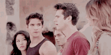a group of young people are standing next to each other in a room and looking at something .