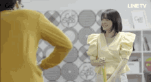 a woman in a yellow shirt is standing next to a man in a yellow shirt and the word line tv is on the bottom of the screen