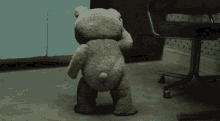 a teddy bear is standing in a room with the word shit written on the floor