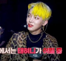 a man with yellow hair is wearing a leopard print shirt and necklace