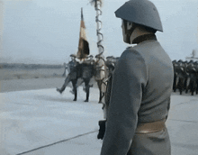 a man in a helmet stands in front of a group of soldiers holding flags