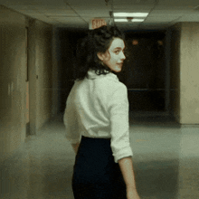 a woman is walking down a hallway with an exit sign above her
