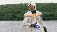 a man in a white and gold costume is standing next to a lake