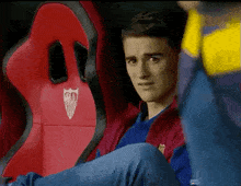 a man is sitting in a red chair with the number 80 on it .