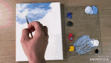 a person is painting a cloudy sky on a canvas next to a palette
