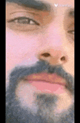 a close up of a man 's face with a beard and a pink lip .