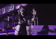 a woman wearing a black shirt with a picture of mickey mouse on it stands on a stage