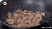 a wok filled with meat is being cooked on a stove ..