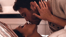 a man and woman are kissing while laying in bed .