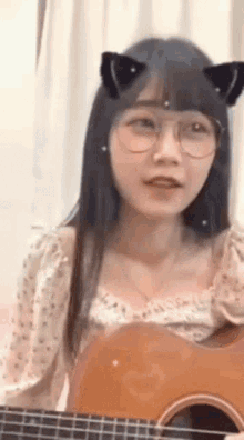 a girl with cat ears is playing a guitar .