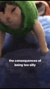 a stuffed animal wearing a green hat and sunglasses is crawling on its back on a bed .