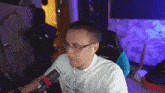 a man wearing glasses and ear buds is sitting in front of a computer .