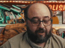 a bald man with glasses and a beard looks at something