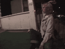 a woman in a white shirt is standing in front of a wooden box