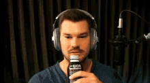 a man wearing headphones is drinking a soda from a can .
