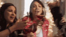 three women toasting with wine glasses in front of a window