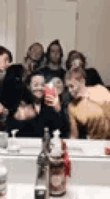 a group of people are taking a selfie in front of a mirror in a bathroom .