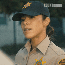 a woman in a sheriff 's uniform is wearing a hat that says countdown on it