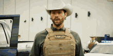 a man in a cowboy hat is wearing a vest that says ranger