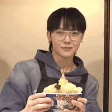 a man wearing glasses is holding a bowl of food in his hands