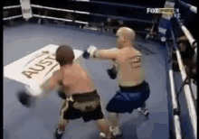 two men are boxing in a ring with a sign that says aus