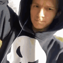 a man wearing a hoodie with a skull on it is taking a selfie .