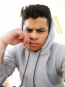 a man wearing a grey hoodie is making a face