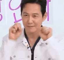a man is making a heart shape with his hands while wearing a white jacket .