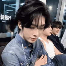 a man wearing earphones looks at his phone