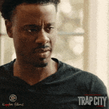 a movie poster for trap city shows a man looking out a window