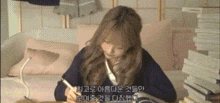 a woman is sitting at a desk with a pen in her hand and a stack of books .