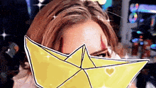 a woman with a yellow paper boat covering her face