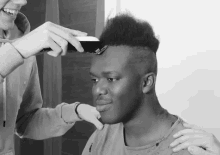 a man is getting his hair cut by another person
