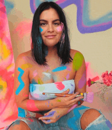 a woman covered in paint holds a brush in her hand
