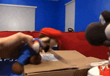 a person is holding a stuffed mario and a stuffed yoshi in a cardboard box .