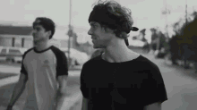 two men are walking down a street and one has a headband on his head