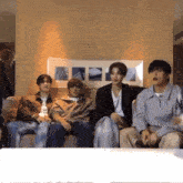 a group of young men are sitting on a couch talking to each other .